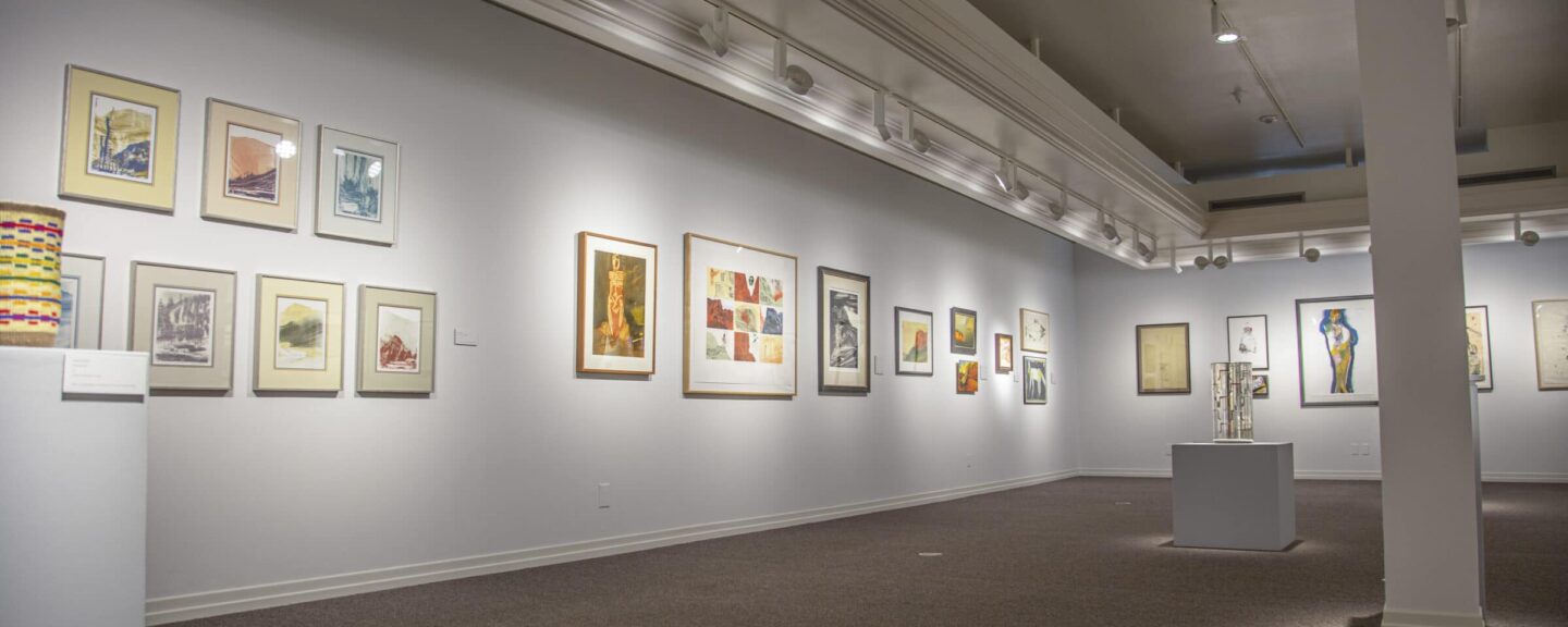 Gallery space with many artworks hung on the wall 