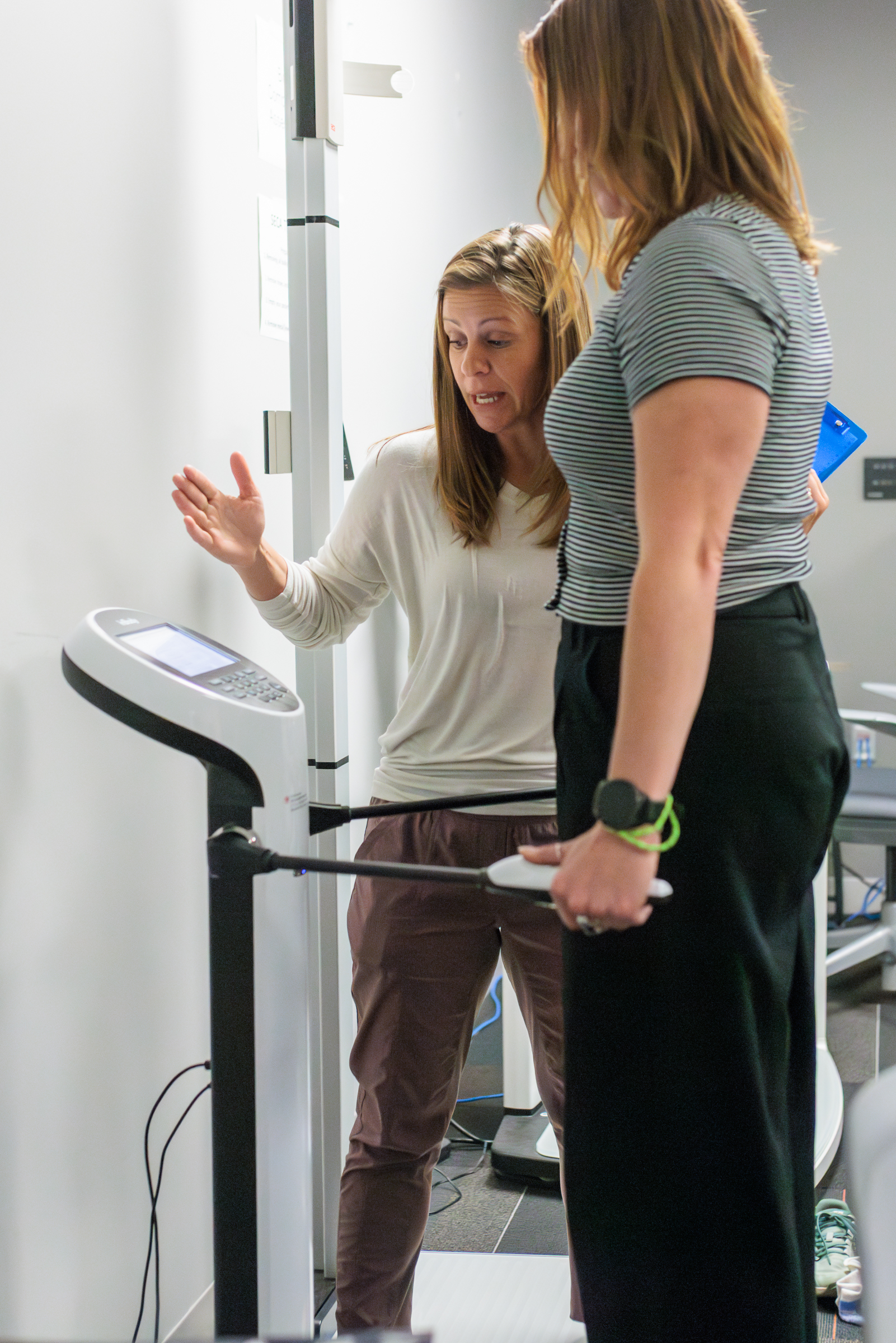 Brooke de Heer helps a participant use the full body biometric measuring device.