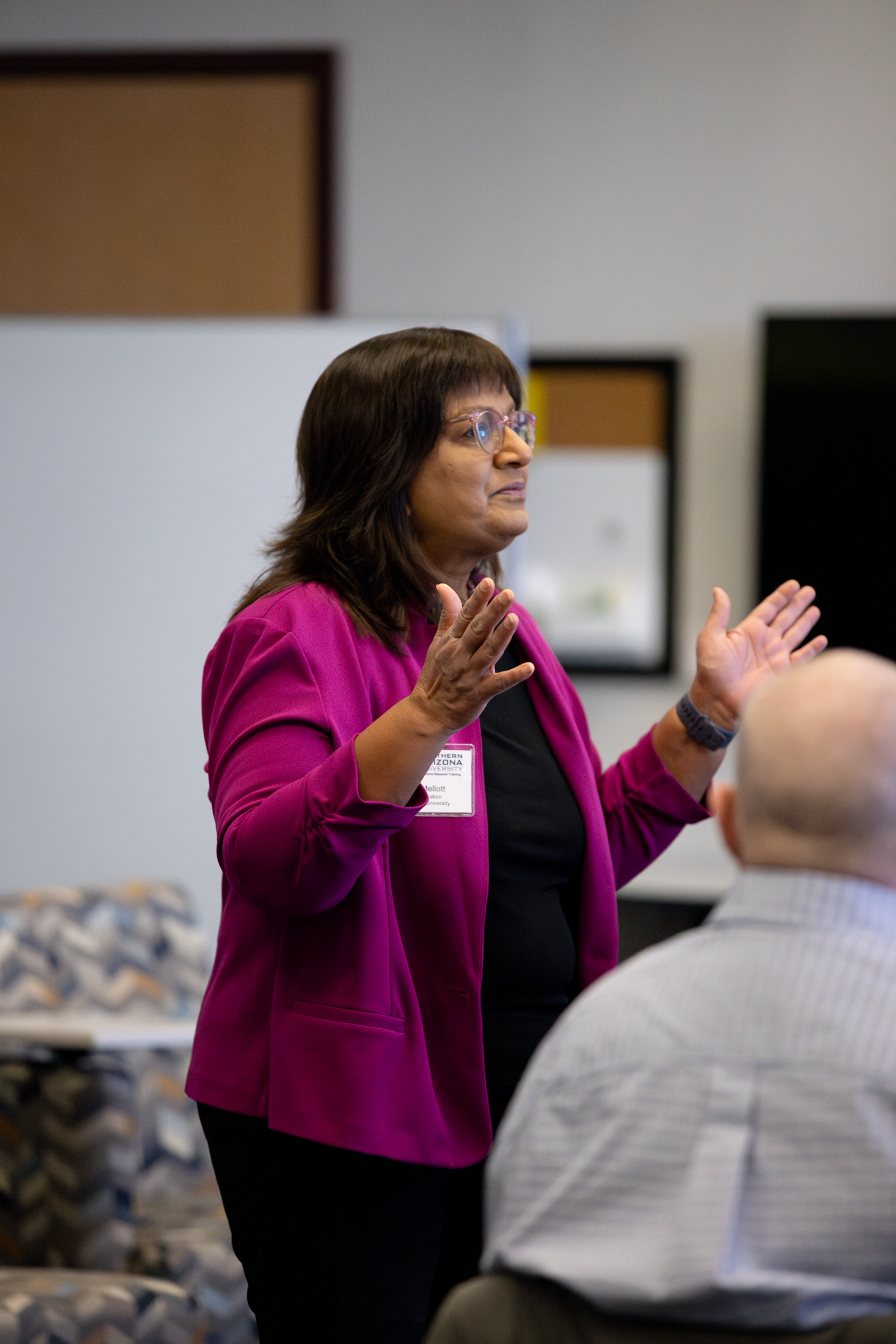 Speaker in pink jacket speaks at C-CART conference.