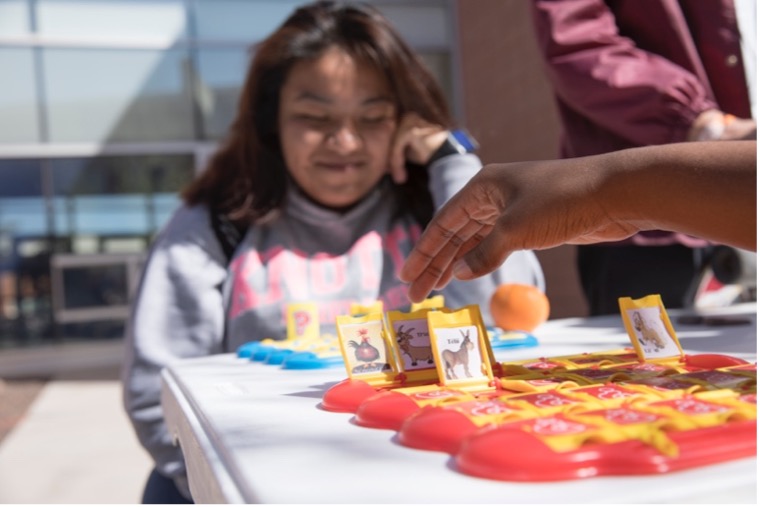 Girl playing game of guess who to practice their language skills.