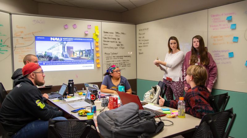 Students working on project at table with many white boards