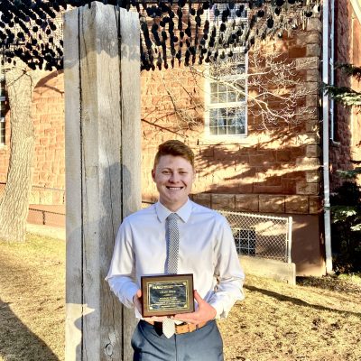Craig poses with award outside of Riles Building