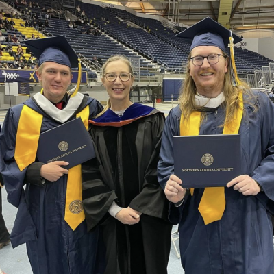 History grads pose with chair, Leila Daniels at graduation