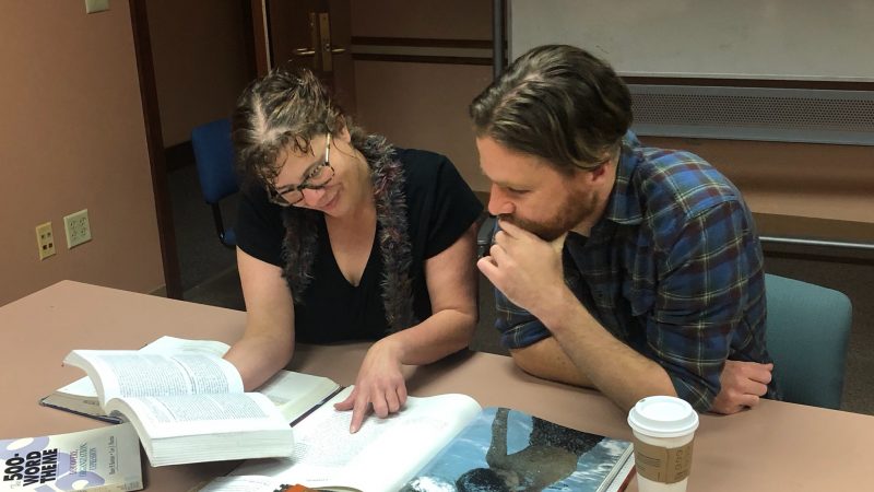 Trace and a student look at a source