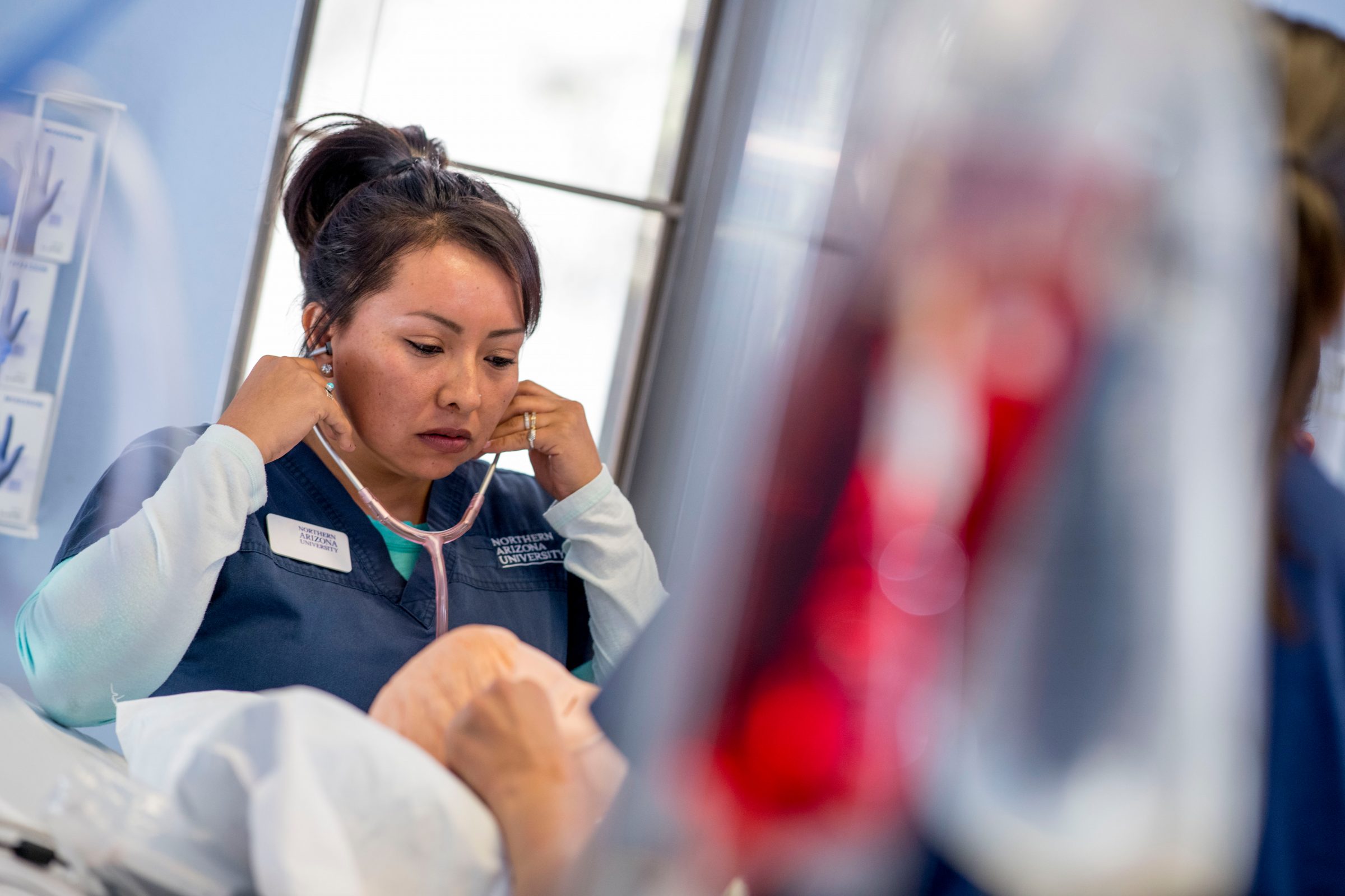 A nurse holding a stethoscope to her ears.
