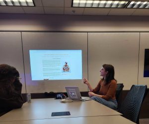 A student gestures at a screen on the wall.