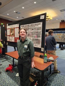 A man stands in front of a pink and black poster.