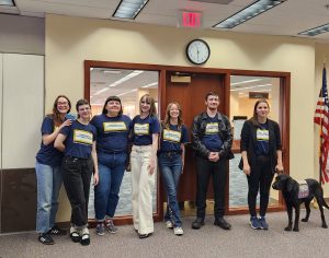 CCS interns wearing CCS t-shirts stand together with a service dog.