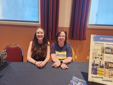 two women smile from behind a table
