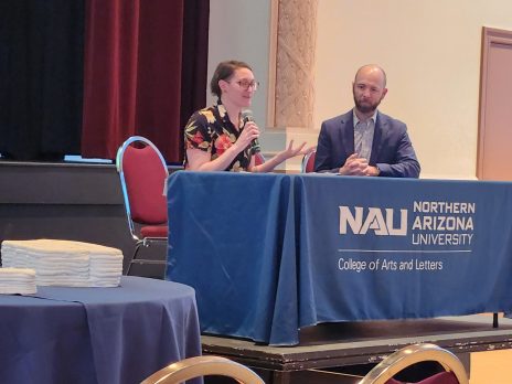 two people speak at an event from a stage