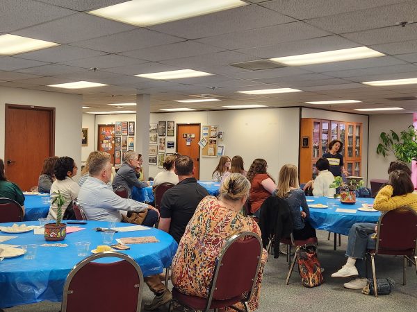 a crowd of people listen to a speaker at a sit-down event