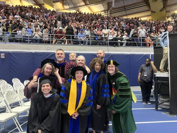 A group of faculty in regalia pose at graduation.