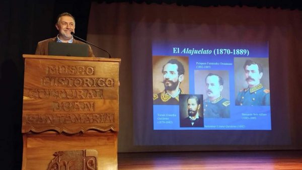 A man in a suit stands in front of a podium.