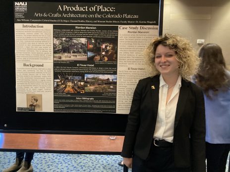 student smiles in front of a poster