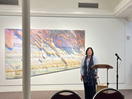 Dr. Pratt-Sturges poses in front of art at an exhibition