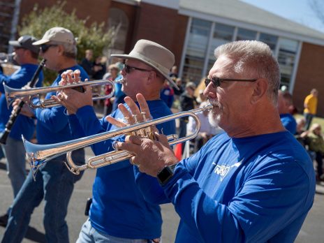 N A U alumni men playing trumpets in a parade.