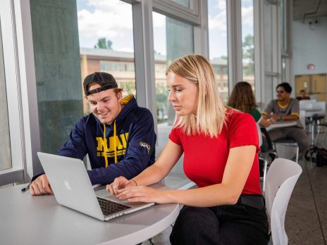 Students studying at a table and smiling