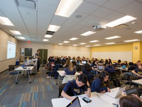 students being lectured by a teacher in a big classroom