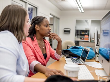 a student helping another on a computer