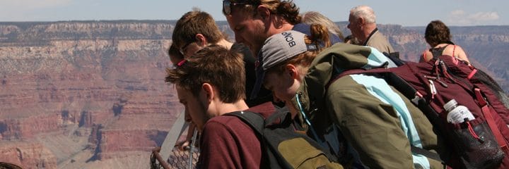 Honors students lean and look into a canyon