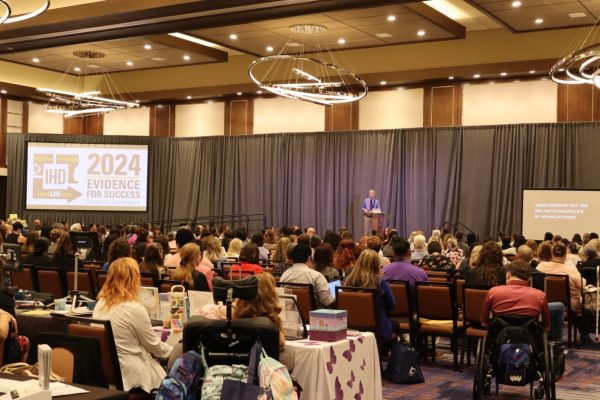 wide shot of stage at IHD conference showing the screen and audience members