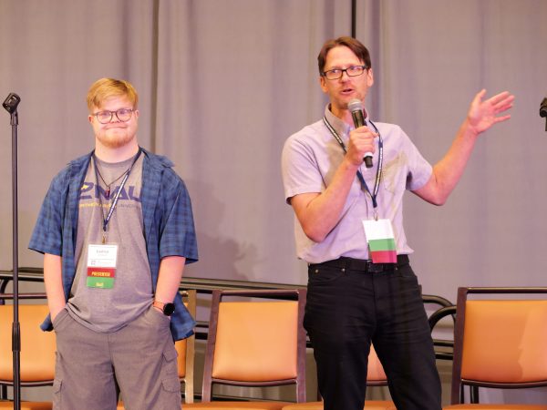 2 men presenting to a group. One is talking into a microphone