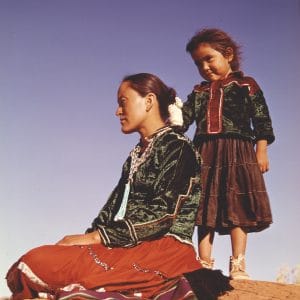 Profile of Young Navajo Mother and Child, Navajo Indian Reservation, Arizona. Wearing their traditional costume, they become part of the fascination of this redrock land. [Photographer's caption]