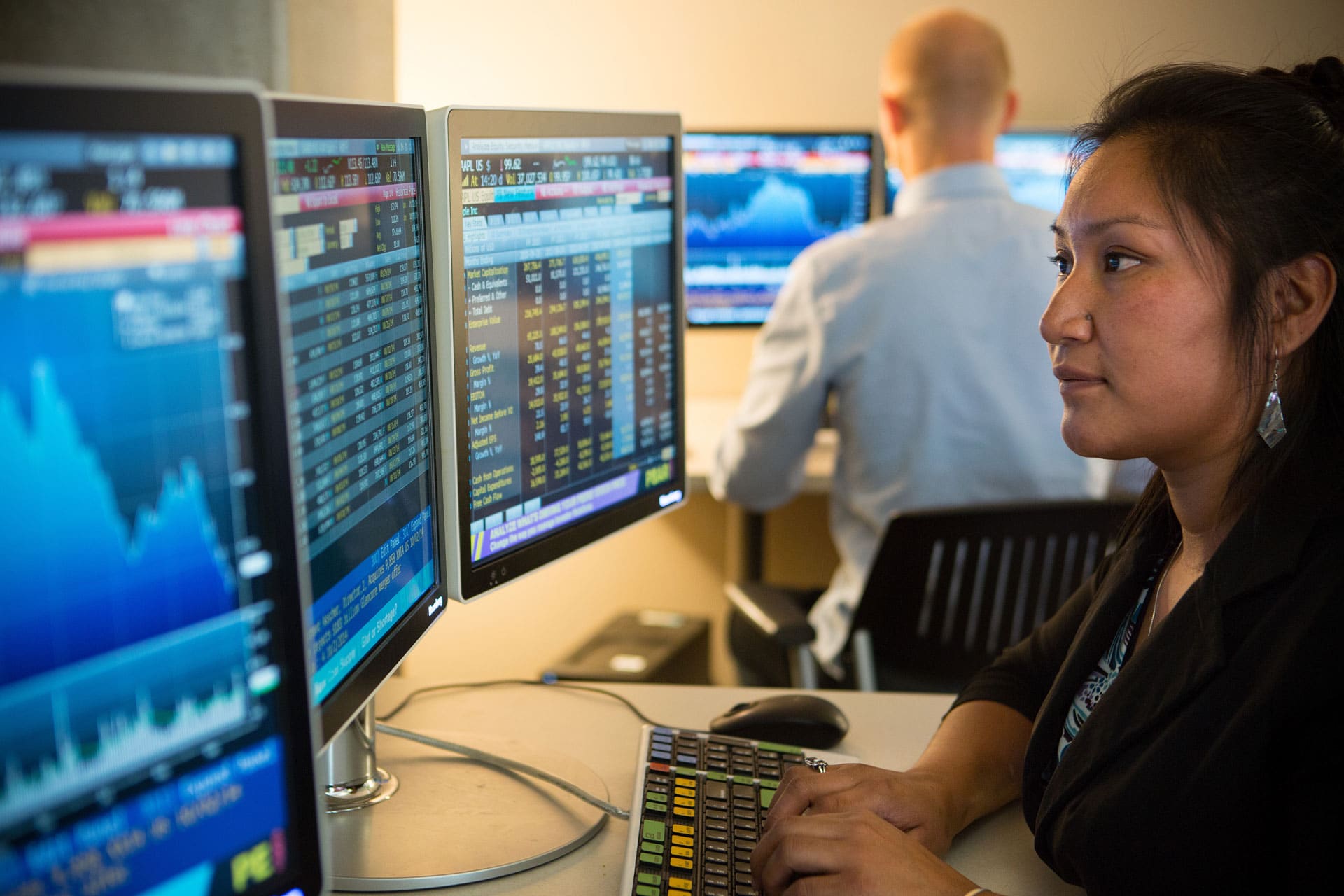 NAU student works on dual monitor computer reviewing stock prices.