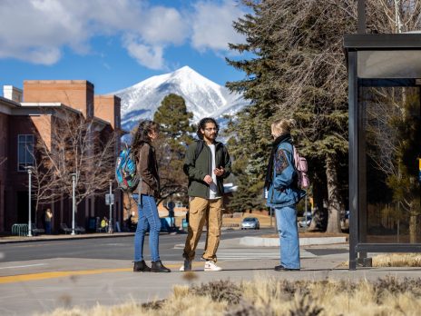 Three students talking on campus with the San Francisco Peaks in the background
