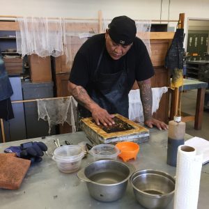 A student processes a lithograph stone in preparation for printing