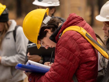 Student writing note son clipboard.