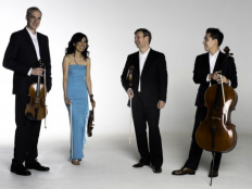Members of The Borealis Quartet standing with stringed instruments wearing formal attire and laughing.
