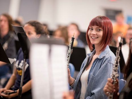 student smiles at camera while holding a clarinet