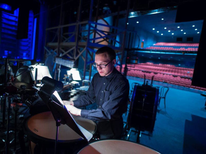 student reads sheet of music in dimly lit auditorium