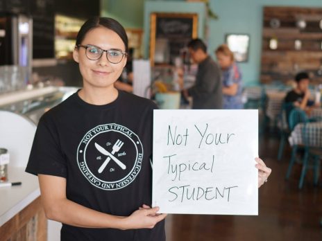 Danielle Curley holds a sign reading "Not Your Typical Student" at “Not Your Typical Deli” in Gilbert, AZ, where she helped train teens and adults with developmental disabilities in professional best practices