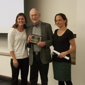 Professor David McKell stands with his NASW Lifetime Achievement Award, between presenters Katherine Mommaerts (left) and Melissa Riggs (right)