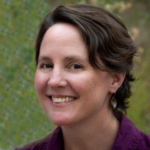 Portrait of Anita Antoninka. She is smiling and has short, brown hair and is wearing a purple button-down shirt.