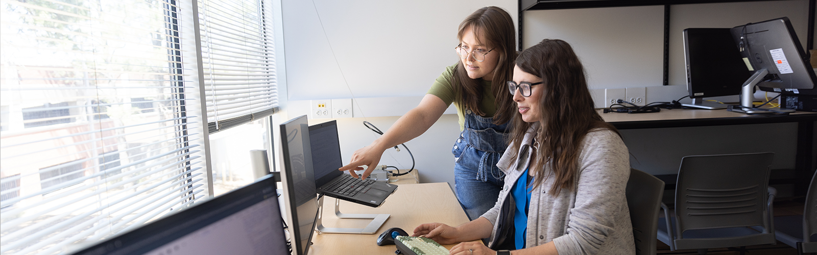 A woman helping another woman with a computer.