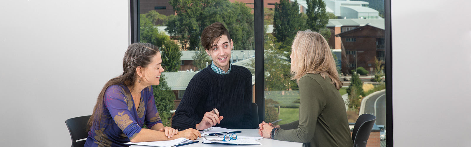 Three staff members having a meeting taking notes.