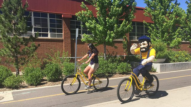 Louie and student riding yellow bikes
