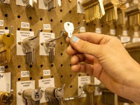 Display of various keys and keycords on a pegboard. Hand reaching to grasp one of the keys.