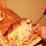 Thanksgiving turkey being cut and served on a wooden table