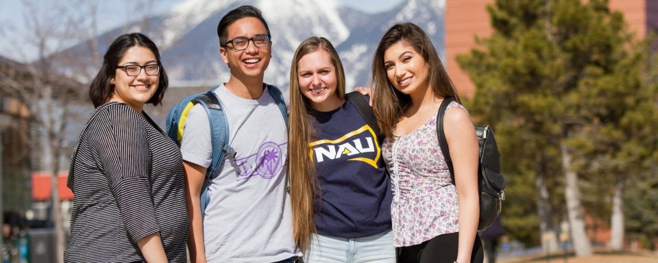 Small group of NAU students smiling on NAU campus. 