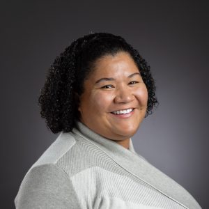 Head shot of Charlese smiling and wearing an off white top