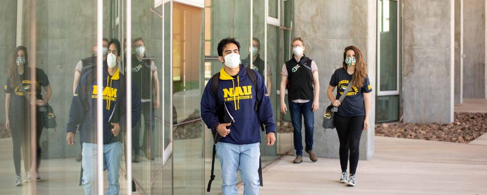 Three masked NAU students walk outside a science building.