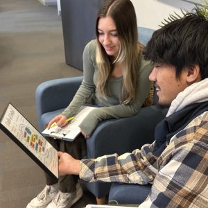 Two students sitting and talking about a stress resource. 