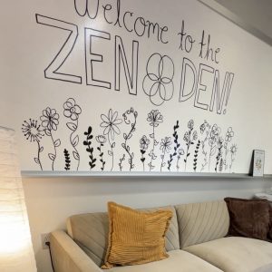 Couch with a white board that says "Welcome to the Zen Den" behind it.