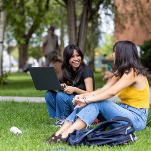 Two students laughing in the grass