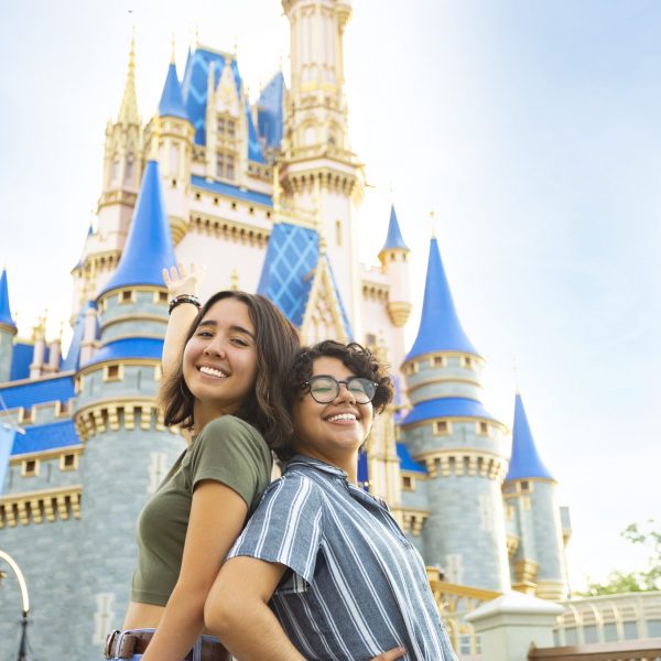 Photo of two students standing back to back in front of the Disney castle.