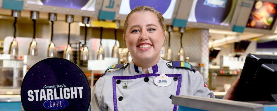 Photo of a Disney employee holding a Starlight Cafe sign in front of the cafe counter.